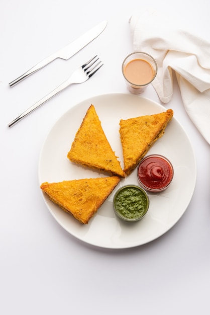 Sanduíche de pão Pakora ou pakoda em forma de triângulo servido com ketchup de tomate, chutney verde, lanche indiano popular na hora do chá