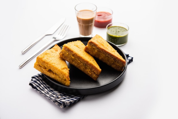 Sanduíche de pão Pakora ou pakoda em forma de triângulo servido com ketchup de tomate, chutney verde, lanche indiano popular na hora do chá