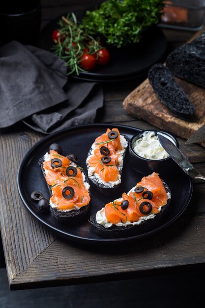 Sanduíche de salmão saudável com cream cheese e pão preto no escuro