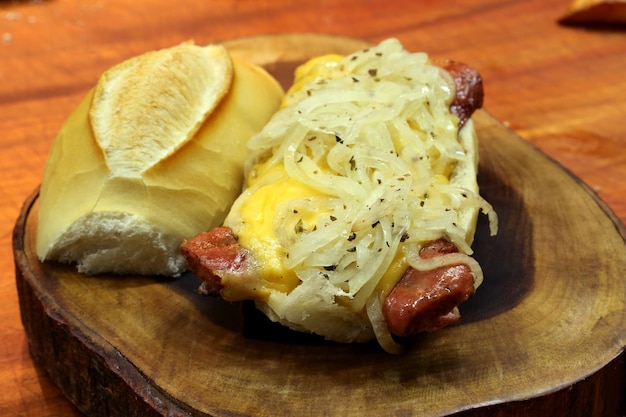 Sanduíche de salsicha da calábria choripan com queijo e cebola em um fundo de madeira