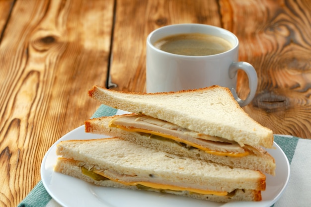 Sanduíche de torrada no prato e xícara de café no guardanapo na mesa de madeira