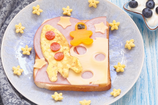 Sanduíche engraçado com foguete e um cosmonauta na lua do queijo