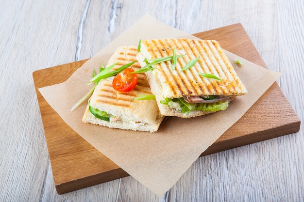 sanduíche frito com carne cogumelos vegetais em papel e tábua de madeira