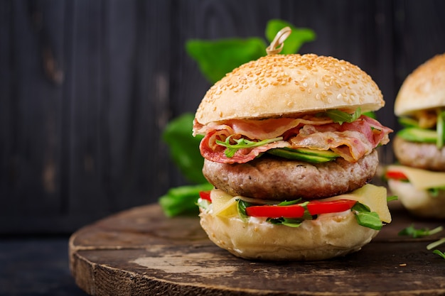 Sanduíche grande - hambúrguer hambúrguer com carne, queijo, tomate, pepino e bacon frito.