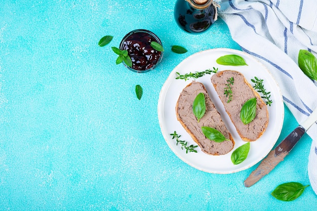 Foto sanduíche grelhado com pate com fígado de frango e azeitonas em fundo azul