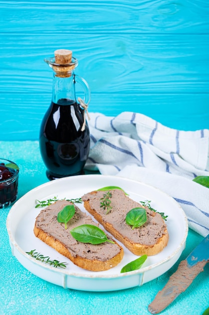 Sanduíche grelhado com pate com fígado de frango e azeitonas em fundo azul