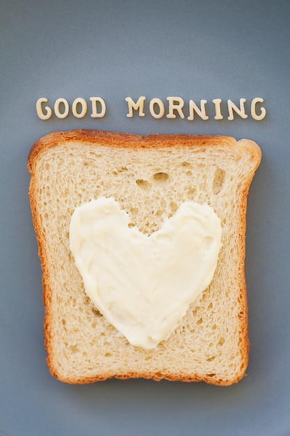 Sanduíche para o café da manhã em forma de coração com queijo em uma placa azul inscrição bom dia