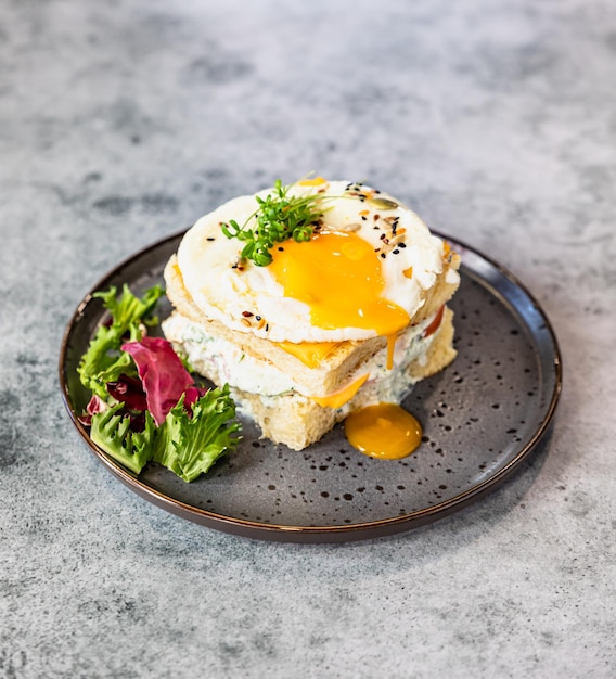 Sanduíche quente francês Croque Madame com presunto queijo ovo frito e salada Delicioso café da manhã