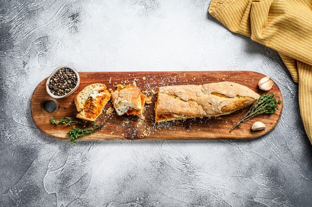 Sanduíche submarino vegetariano baguete com berinjela grelhada, pimenta e queijo feta na mesa cinza.