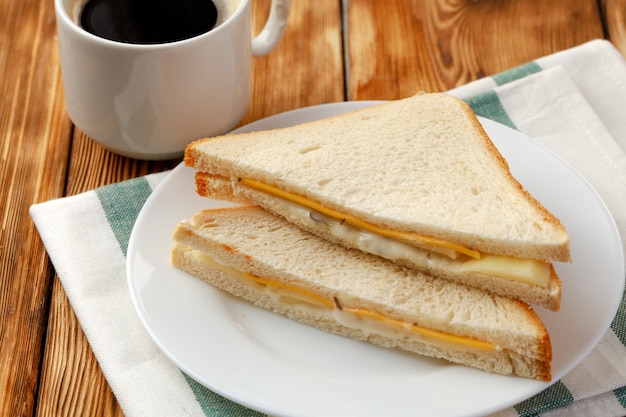 Sanduíche torrada e xícara de café no guardanapo na mesa de madeira