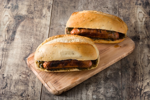 Sanduíche tradicional de Choripan Argentina com molho de chouriço e chimichurri na mesa de madeira