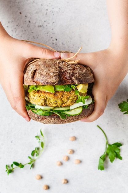 Foto sanduíche vegano com patty de grão de bico, abacate, pepino e verduras no pão de centeio