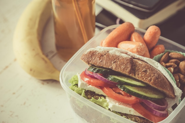 Foto sanduíche vegano na lancheira com cenouras e nozes