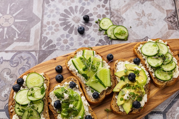 Sanduíche vegetariano com microgreens em uma placa de madeira linda servindo em um fundo brilhante