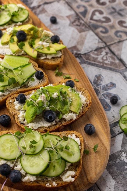 Sanduíche vegetariano com microgreens em uma placa de madeira linda servindo em um fundo brilhante