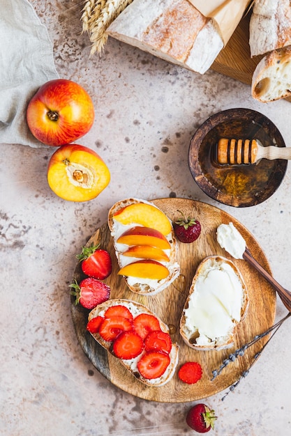 Sanduíches abertos com pão artesanal e cream cheese nectarinas morangos e mel