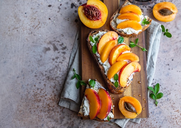 Sanduíches abertos com pão tartine e nectarina de cream cheese e damasco regados com mel