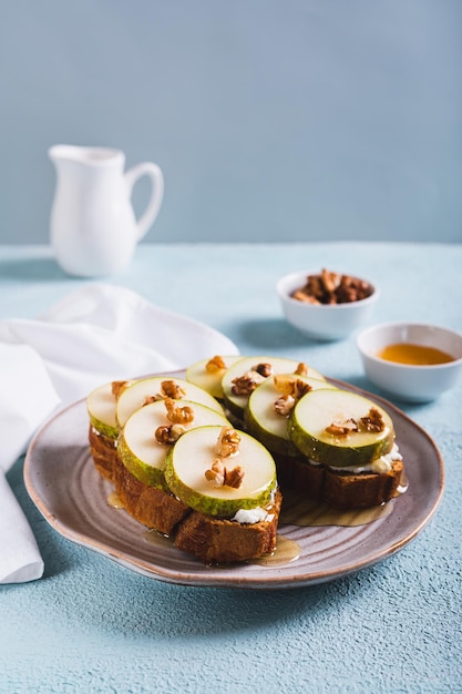 Foto sanduíches apetitosos em pão de centeio com mel de rúcula e nozes em um prato, vista vertical