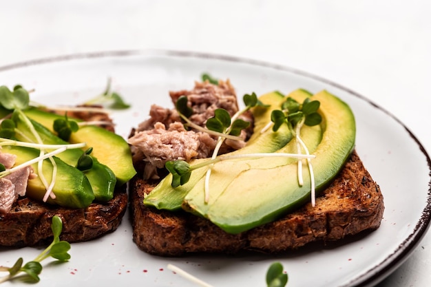 Sanduíches com abacate e atum na tábua de madeira na vista superior de fundo branco Café da manhã saudável ou lanche Fundo de receita de comida Fechar