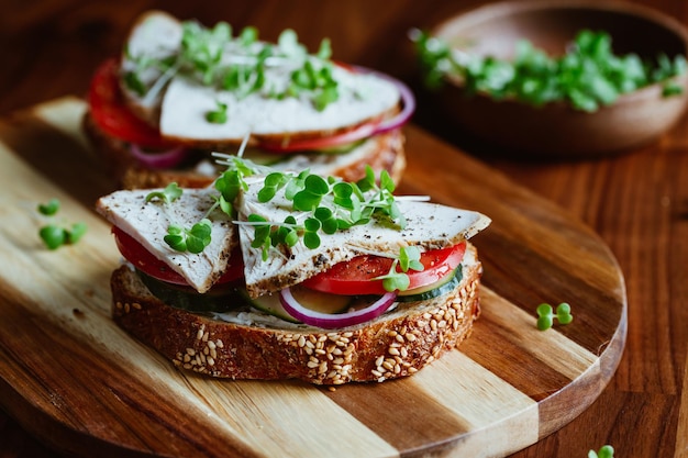 Sanduíches com carne de peru e legumes frescos servidos com microgreens em uma placa de madeira O conceito de alimentação saudável e dietética