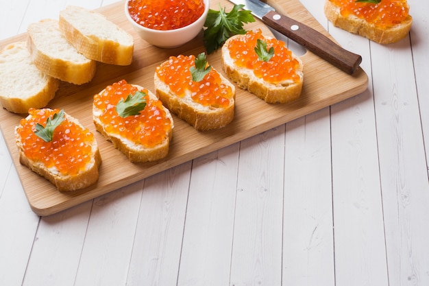 Sanduíches com caviar de salmão vermelho em uma placa de madeira