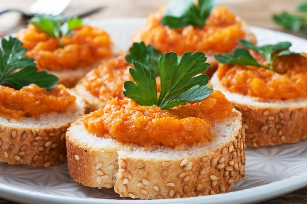 Sanduíches com cebola, pão, abobrinha, caviar, tomate, tomate. Comida vegetariana caseira. Legumes cozidos enlatados. fundo de madeira de perto