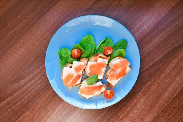 Sanduíches com peixe vermelho em um prato azul. decorado com verduras