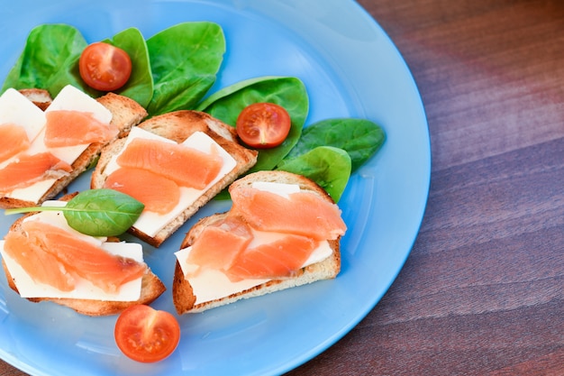 Foto sanduíches com peixe vermelho em um prato azul. decorado com verduras