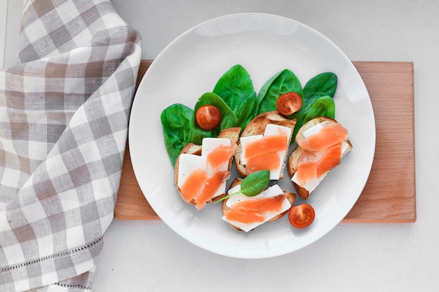 Sanduíches com peixe vermelho em um prato branco. decorado com verduras