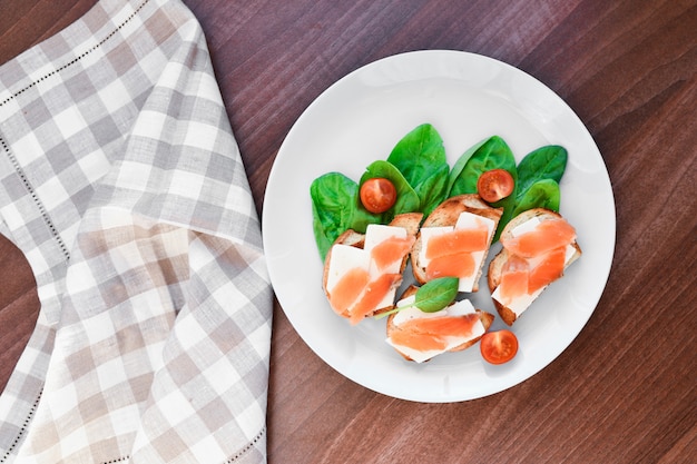 Sanduíches com peixe vermelho em um prato branco. decorado com verduras