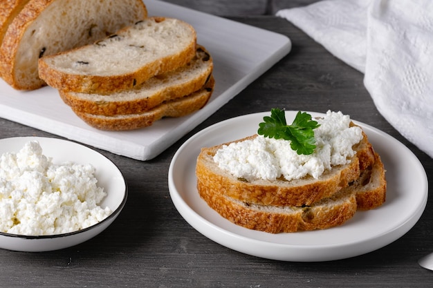 Sanduíches com queijo cottage e pão com azeitonas em uma mesa cinza