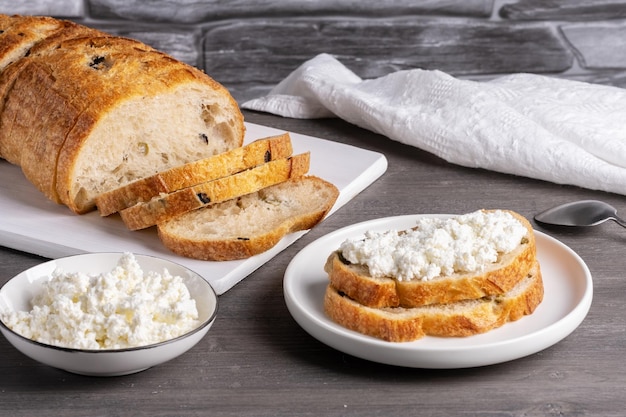 Sanduíches com queijo cottage e pão com azeitonas em uma mesa cinza