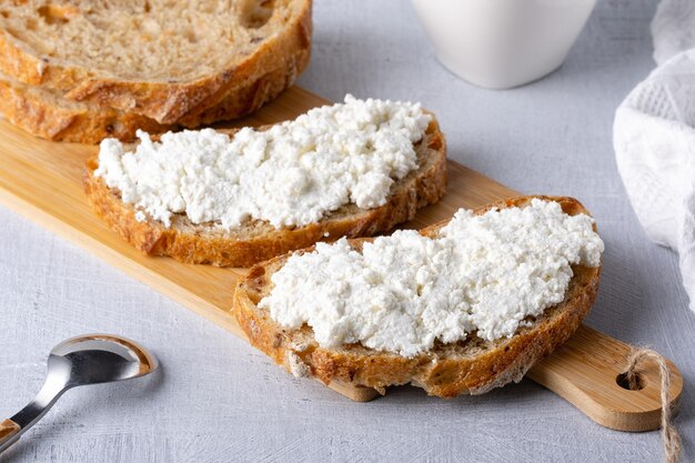 Sanduíches com queijo cottage e pão com azeitonas em uma mesa cinza