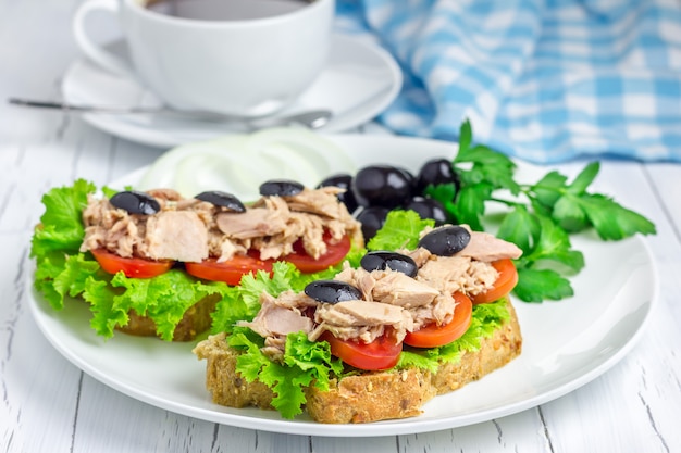 Sanduíches de atum no prato branco e café