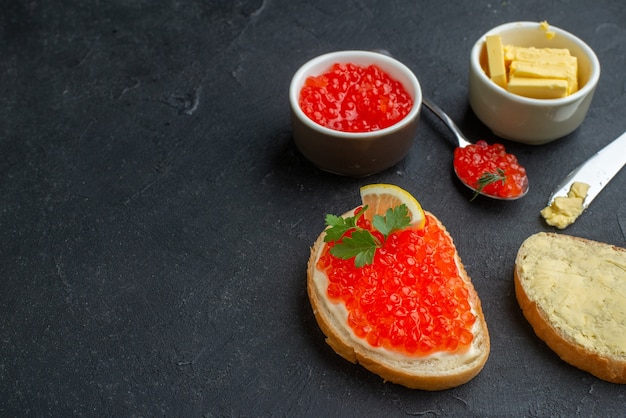 Sanduíches de caviar com limão e queijo na superfície escura