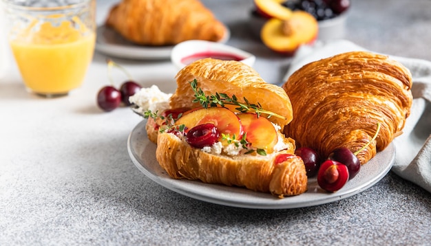 Sanduíches de croissant com cereja nectarina e ricota ou cream cheese com suco no café da manhã