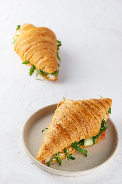 Sanduíches de croissants com cream cheese de salmão e rúcula Orientação vertical.
