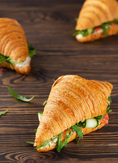 Sanduíches de croissants com cream cheese de salmão e rúcula sobre uma mesa Orientação vertical.