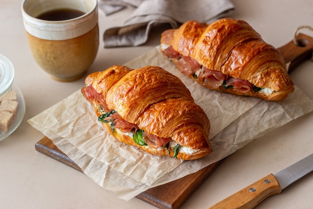 Sanduíches de croissants com presunto, manjericão e queijo branco. Cozinha francesa. Café da manhã.