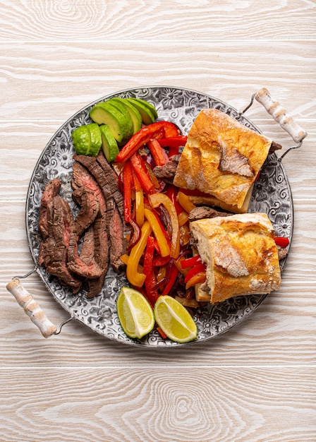 Sanduíches de fajitas feitos de prato tradicional mexicano Fajita de carne e pão branco servido com abacate maduro em um fundo branco rústico de madeira de cima, comida mexicana americana lanche saudável