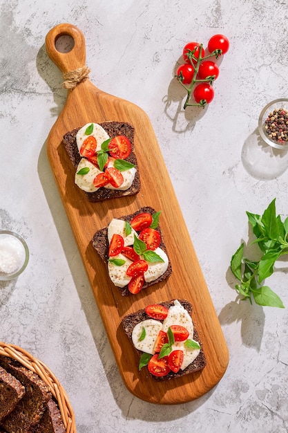 Sanduíches de pão integral com queijo, tomate e folhas de manjericão, vista superior. Conceito de lanche saudável.