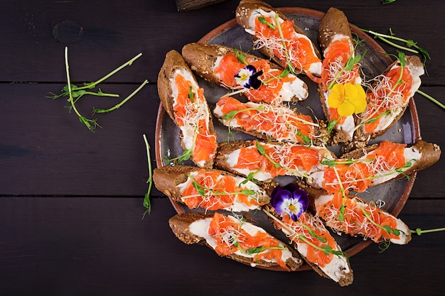 Sanduíches de salmão com cream cheese e microgreen na mesa de madeira