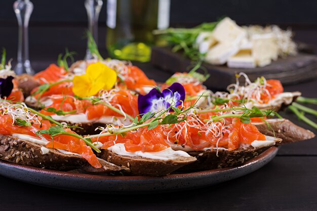 Sanduíches de salmão com cream cheese e microgreen na mesa de madeira