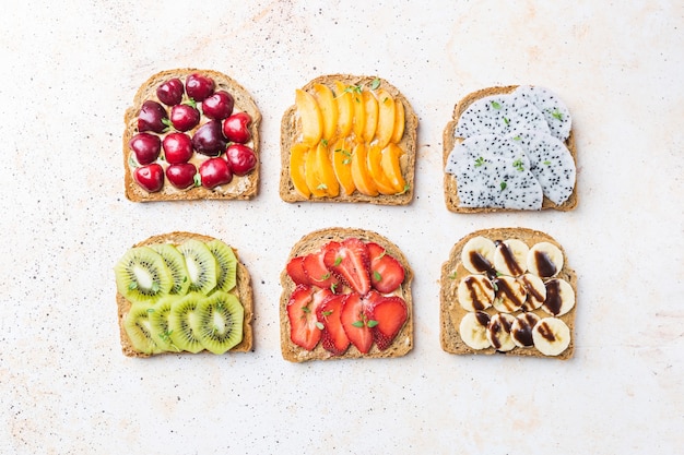 sanduíches de torradas com manteiga de amendoim, morangos e frutas pêssego, morango, banana, cereja, kiwi e fruta do dragão