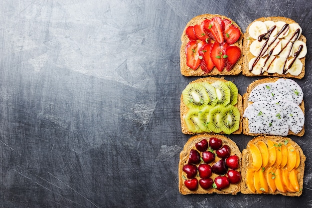 sanduíches de torradas com manteiga de amendoim, morangos e frutas pêssego, morango, banana, cereja, kiwi e fruta do dragão