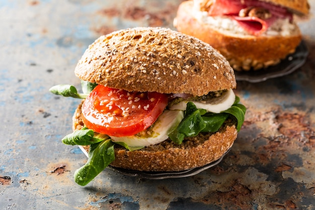 Sanduíches italianos Caprese com tomates frescos, queijo muçarela e alface de cordeiro, pão multigrãos