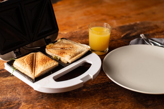 Sanduíches torrados em um sanduíche de torrada um prato vazio e um copo de suco de laranja em um fundo de madeira Lanche de café da manhã leve