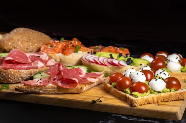 Sanduíches variados com peixe, queijo, carne e vegetais no tabuleiro.