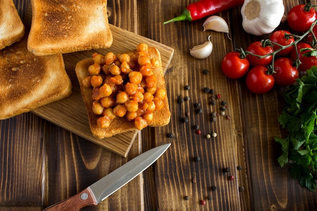 Sanduíches vegetarianos com grão de bico em molho de tomate e ingredientes no fundo de madeira. vista superior.