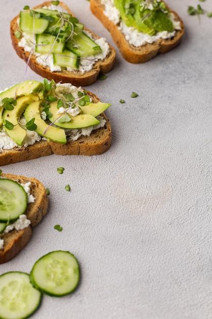 Sanduíches verdes vegetarianos com abacate e pepino com microgreens em um fundo claro